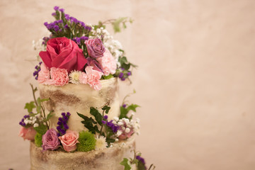 Cake with flower decoration for weddings, birthdays and events. Isolated white naked cake, rustic style on sephia background. Concept: Celebrating Love and Life.