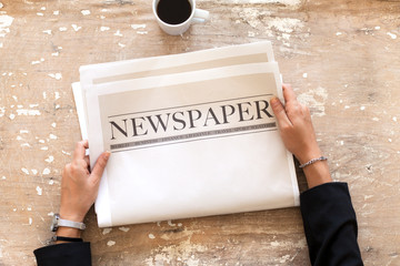 Woman reading newspaper on wooden background