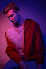 Fototapeta premium Fashion photo portrait of a young male model trendy fashionable urban style in studio on color gel background