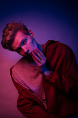 Fashion photo portrait of a young male model trendy fashionable urban style in studio on color gel background