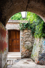Fototapeta na wymiar View of new polished wooden door contrasting with old stone work through brick archway