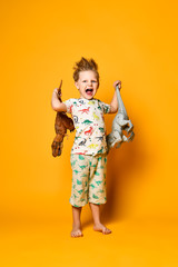 little cheerful boy holds a plastic dinosaur in each hand. The boy is dressed in a suit with...