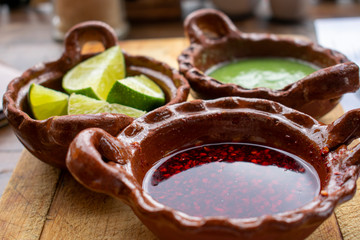Salsa picante verde, salsa de chile de árbol y limones en cazuelas de barro son indispensables como complemento indispensable en la comida mexicana