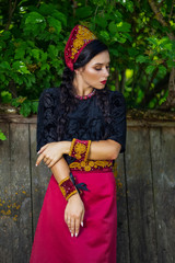 Glamour Fashion Model in Russian Style Decorated Kokoshnik Posing Outdoors Against Old Wooden Fence.