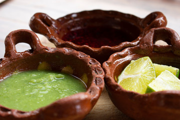 Salsa picante verde, salsa de chile de árbol y limones en cazuelas de barro son indispensables como complemento indispensable en la comidad mexicana