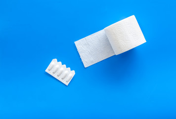 Disease of colon concept with toilet paper roll and rectal suppository on blue background top view