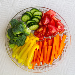Fresh cut up vegetables in a platter; appetizing broccoli, carrots, tomatoes, peppers and cucumbers displayed as a rainbow