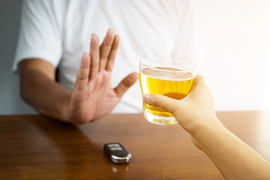 Do not drink and drive! Cropped image of man showing stop gesture and refusing to drink beer. Car keys lying near .Don't drink and drive concept