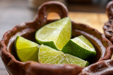 Limones partidos en cazuela de barro sobre mesa para acompañar una comida my mexicana