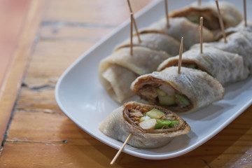 Plate with fresh spring rolls in rice paper on table