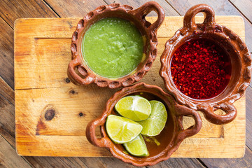 Salsa picante verde, salsa de chile de árbol y limones en cazuelas de barro son indispensables como complemento indispensable en la comidad mexicana