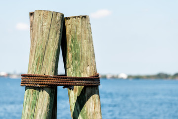 Closeup of anchor wooden bollard on boat pier in Fort Myers Florida with bay of blue water