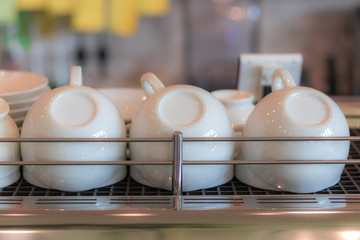 Upside down clean white coffee cups on shelf in the coffee shop