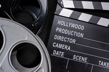 Movie clapper and film reel on a wooden background