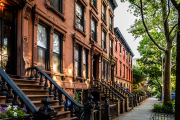 Scenic view of a classic Brooklyn brownstone block with a long facade and ornate stoop balustrades on a summer day in Clinton Hills, Brooklyn - obrazy, fototapety, plakaty