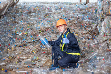 Portrait of Asian Industrial engineer workers with a pile of plastic bottles at the factory for processing and recycling.