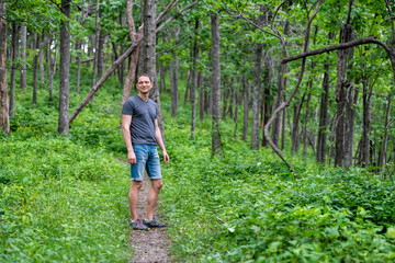 Young happy man standing on Appalachian nature trail in Shenandoah Blue Ridge mountains with green grass lush foliage on path