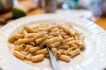 Macro closeup of fresh homemade brown rice penne pasta with olive oil and fork on plate with hot steam