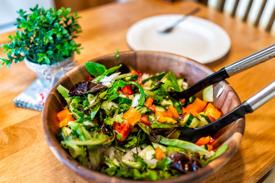 Closeup Of Fresh Green Salad In Bowl Plate With Mixed Lettuce, Bell Peppers With Potted Plant In Rustic Wooden Table