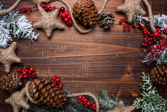 Christmas decorations on a brown wood background with copy space. Pine cones, garland, berries and pine branches