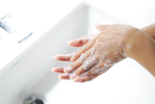 Closeup woman's hand washing with soap in bathroom, selective focus
