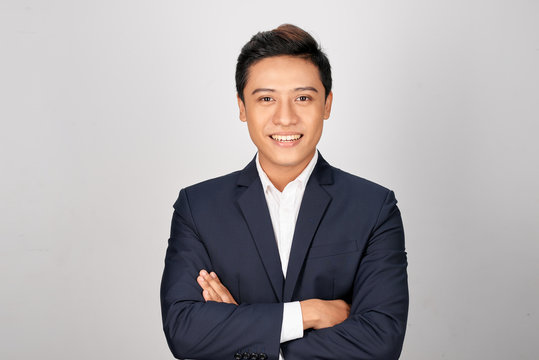 Happy Asian Young Businessman Standing Cross-armed On White Background