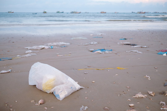 Trash, plastic, garbage, bottle, bag ... environmental pollution on the sandy beach. Royalty high-quality stock photo image of trash, plastic bag on sand beach. Waste that polluted ocean environment