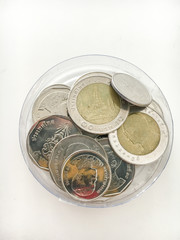 Many Thai coins in the selection of the focus on the glass bottle above the white background