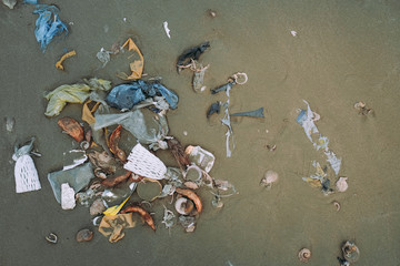 Trash, plastic, garbage, bottle, bag... environmental pollution on sandy beach. Royalty...