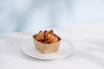 Croissant with raspberries. Raspberries with croissants. Croissant on a light background with raspberry berries