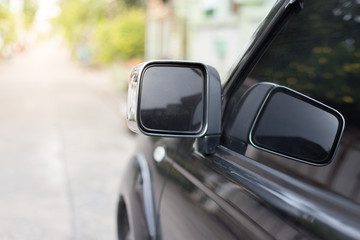 Side mirror of black car on blurred background