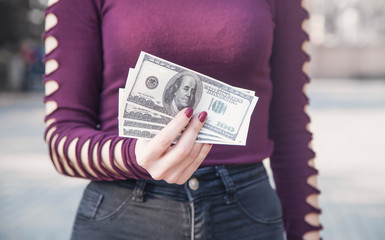 Woman holding dollar banknotes in outdoors.