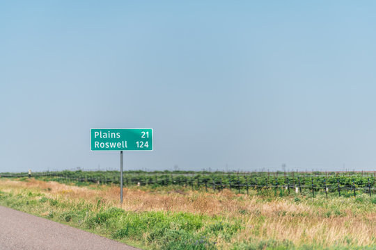 Brownfield, USA Texas countryside industrial town sign for Plains and Roswell New Mexico miles on road direction view from 380 highway