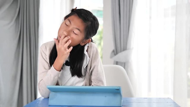 Asian girl picking her nose while using digital tablet at home, lifestyle concept.