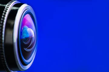 Camera lens with blue backlight. Side view of the lens of camera on blue background. Blue camera Lens close Up.