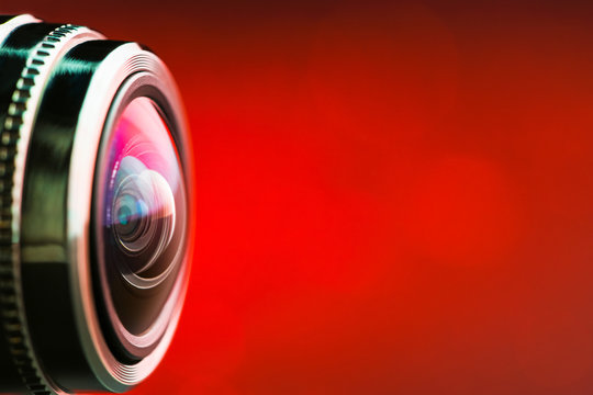 Camera lens with red backlight. Side view of the lens of camera on red background. Red  camera Lens close Up. Gorizontal photo
