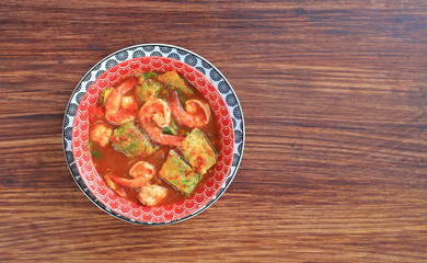 Delicious Thai yellow curry with shrimp and fried herb vegetable omelet in bowl on wooden table background with copy space.