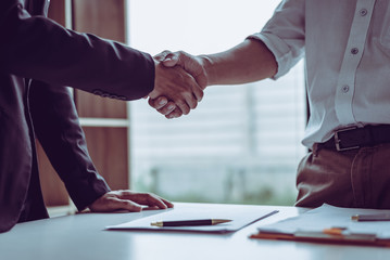 Middle age Asian partner lawyers attorneys shaking hands after discussing a contract agreement done.