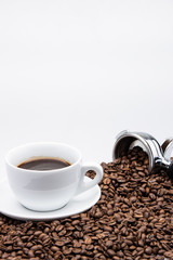 cup of coffee with coffee beans and machine on white background