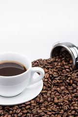 cup of coffee with coffee beans and machine on white background
