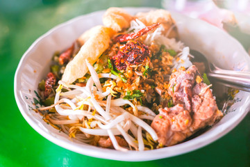 rice noodle with pork , bean sprouts, crispy pork skin, chili powder and clear soup is served at street food  in Chiangmai,  Thailand