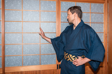 Traditional japanese house or ryokan onsen with man in kimono opening shoji sliding paper doors with hand