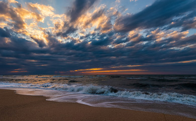 Beach with waves at colorful sunset