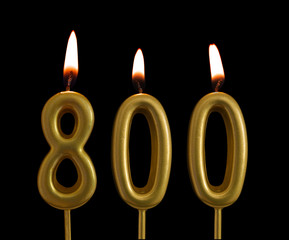 Golden birthday candles isolated on black background, number 800