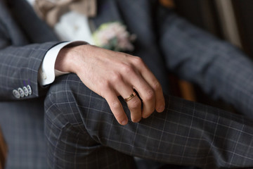 Obraz premium classic engagement ring on the groom's hand. Wedding ring on the groom's finger. Checkered blue men's suit. Button down jacket cuffs
