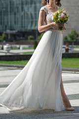 Plakat light airy wedding dress with a slit for the legs. The bride walks in a simple elegant wedding dress. White dress with a high slit flutters in the wind during a walk.