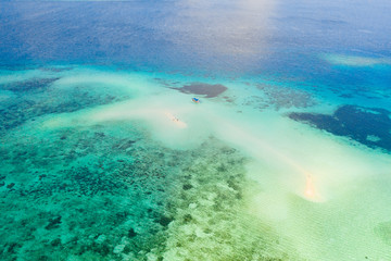 Coral reef with turquoise water and sandy shoals. Large atoll with beautiful lagoons. Tourists relax in the warm sea water. Tropical sea, view from above.