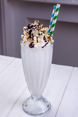 Milk bright coctail with whipped cream in glass decorated with popcorn and cholocale. Summer coctails. Menu of cafe or restaurant