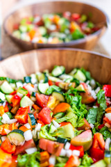 Vertical closeup of two fresh salad in wooden bowls plates with romaine lettuce and bell peppers