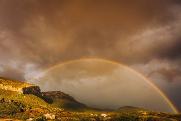 Fototapeta na wymiar Rainbow on dark cloudy sky in Greece